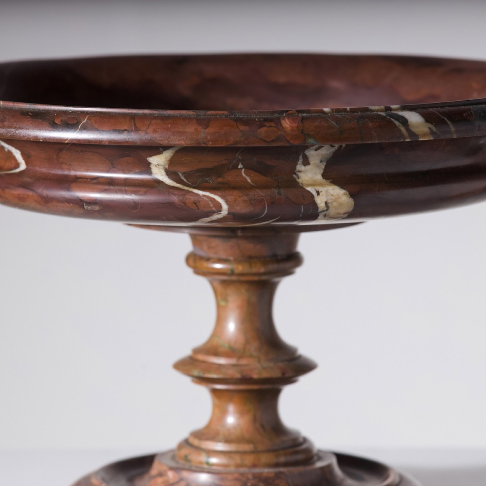 A carved reddish-brown marble tazza featuring a wide shallow dish, turned central stem, and circular moulded base. View VII