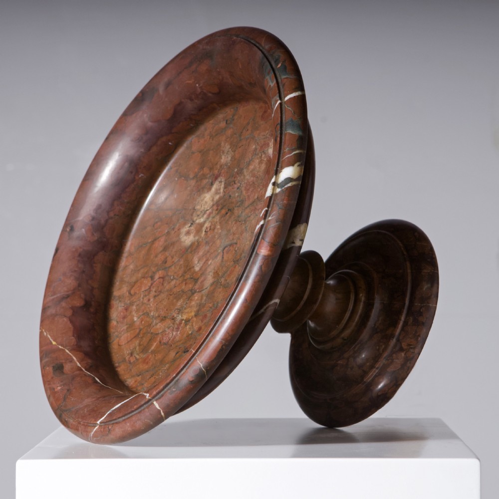 A carved reddish-brown marble tazza featuring a wide shallow dish, turned central stem, and circular moulded base. View IX