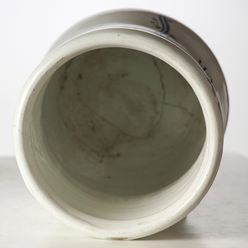 A cylindrical 19th-century tin-glazed ceramic pharmacy jar featuring a blue painted scrollwork cartouche with Latin text. View V