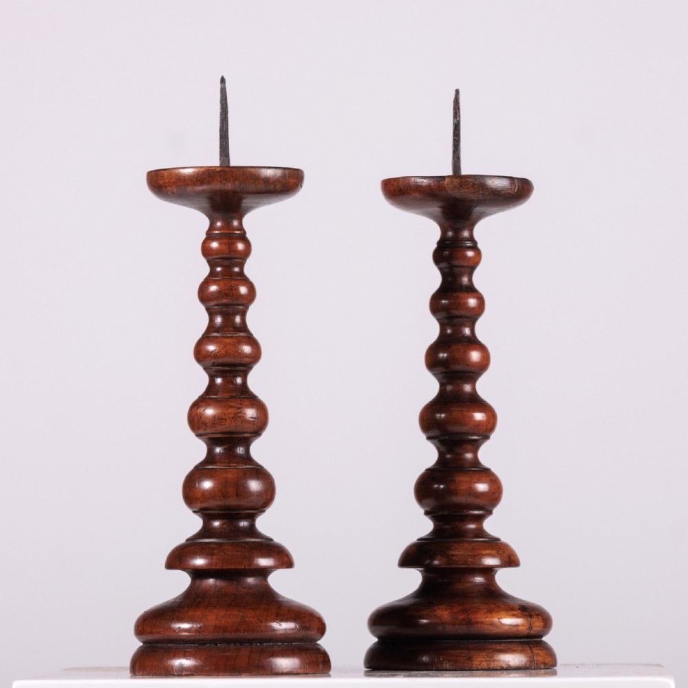 A pair of 18th-century turned dark wood pricket candlesticks featuring iron spikes and stepped circular bases. View V