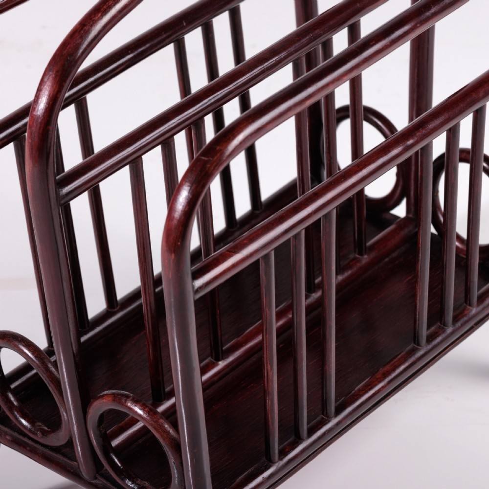 A dark reddish-brown bentwood magazine rack featuring a central arched carrying handle, vertical spindles, and circular bentwood side accents. View III