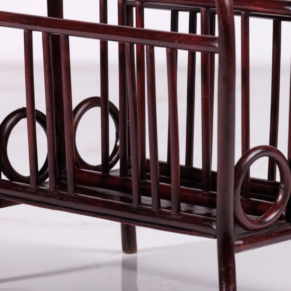 A dark reddish-brown bentwood magazine rack featuring a central arched carrying handle, vertical spindles, and circular bentwood side accents. View IV