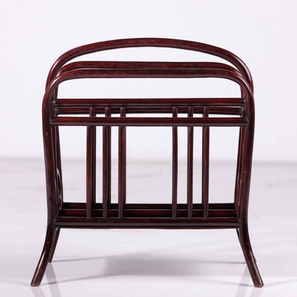 A dark reddish-brown bentwood magazine rack featuring a central arched carrying handle, vertical spindles, and circular bentwood side accents. View VI