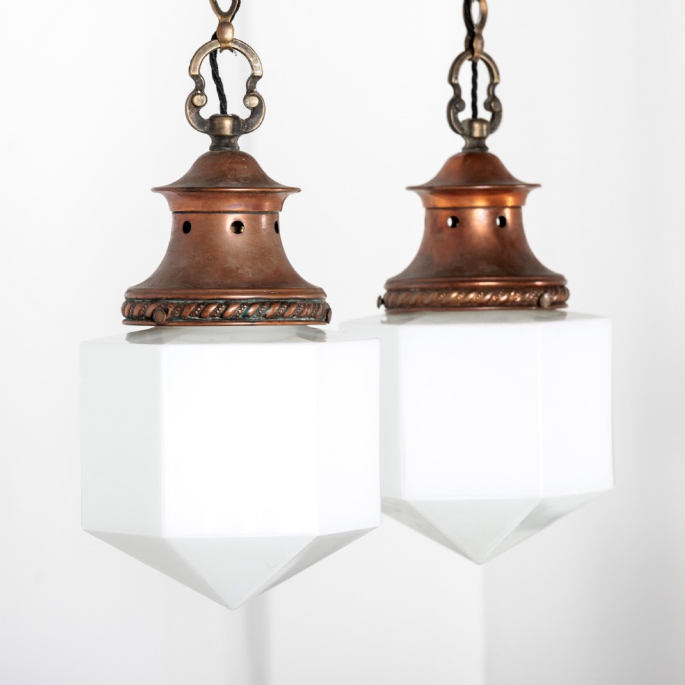A pair of 1930s Art Deco pendant lights featuring faceted white opal glass hexagonal shades and flared copper top galleries with hanging loop attachments. View III