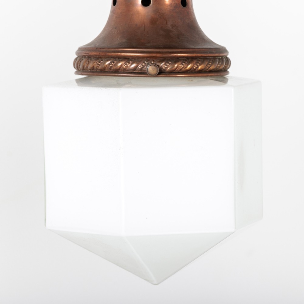 A pair of 1930s Art Deco pendant lights featuring faceted white opal glass hexagonal shades and flared copper top galleries with hanging loop attachments. View VI