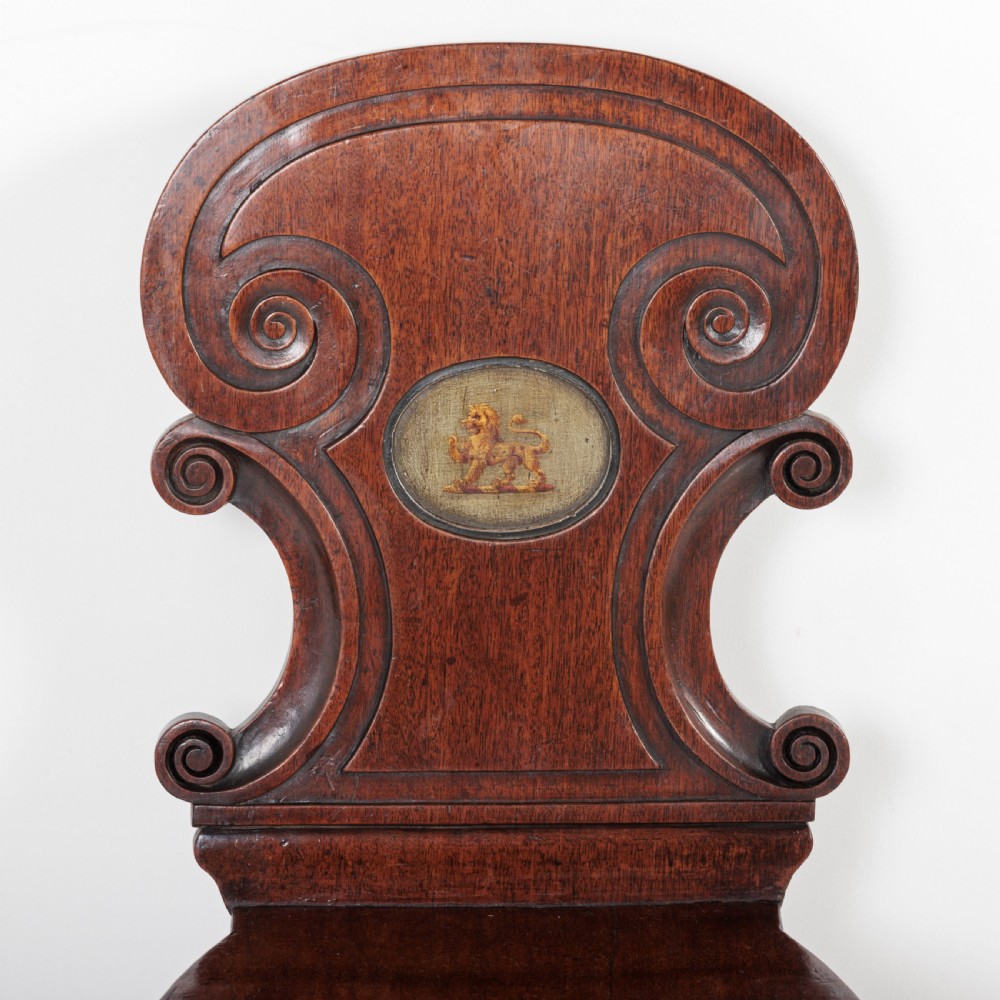 A pair of 19th-century dark mahogany hall chairs featuring scroll-carved backrests with central circular medallions and curved front legs. View III