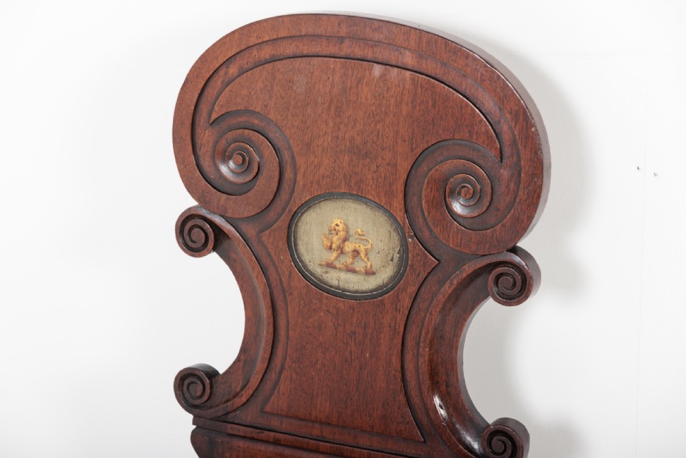 A pair of 19th-century dark mahogany hall chairs featuring scroll-carved backrests with central circular medallions and curved front legs. View IV
