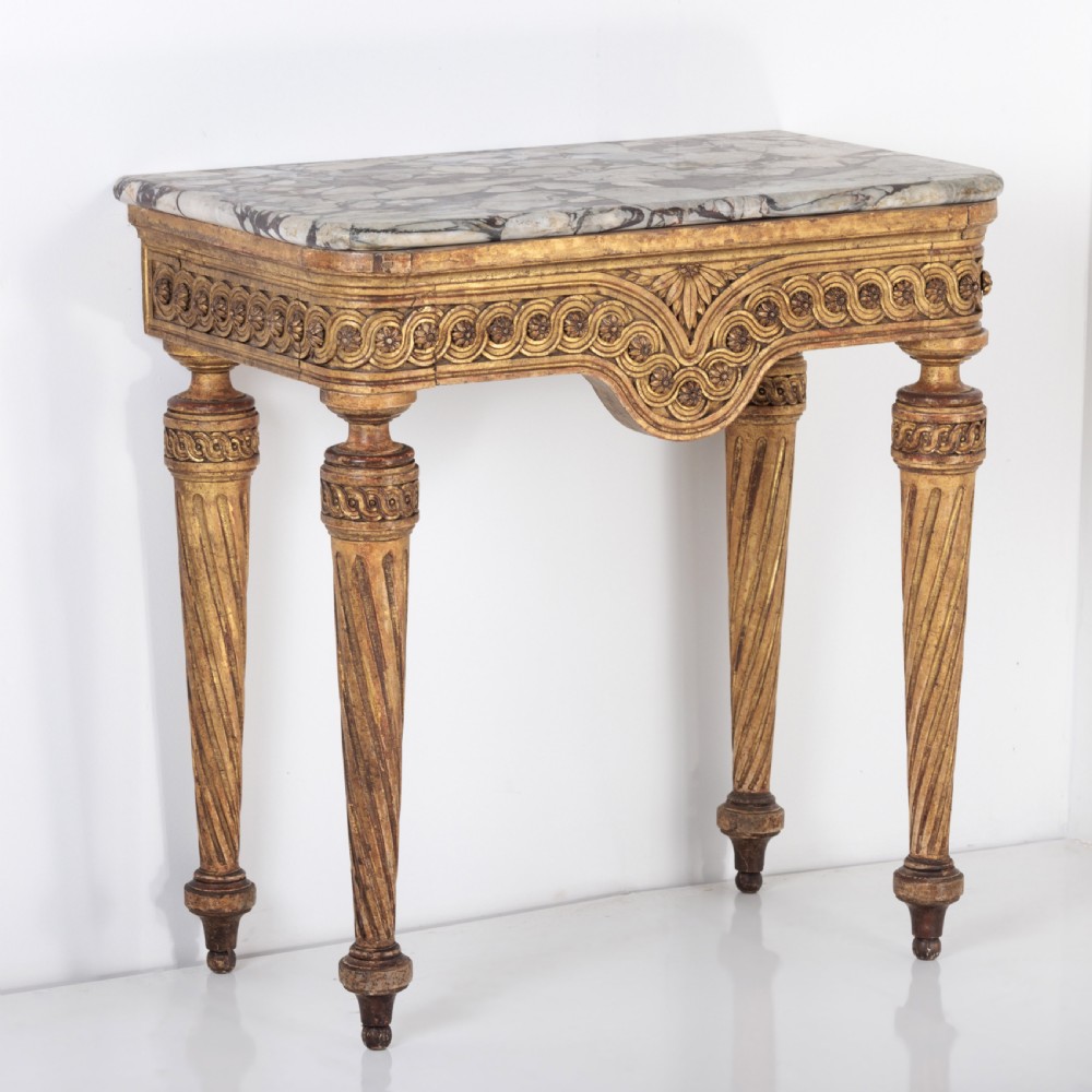 A 19th-century French giltwood console table featuring a grey and white marble top, carved guilloche apron, and spirally fluted tapered legs.