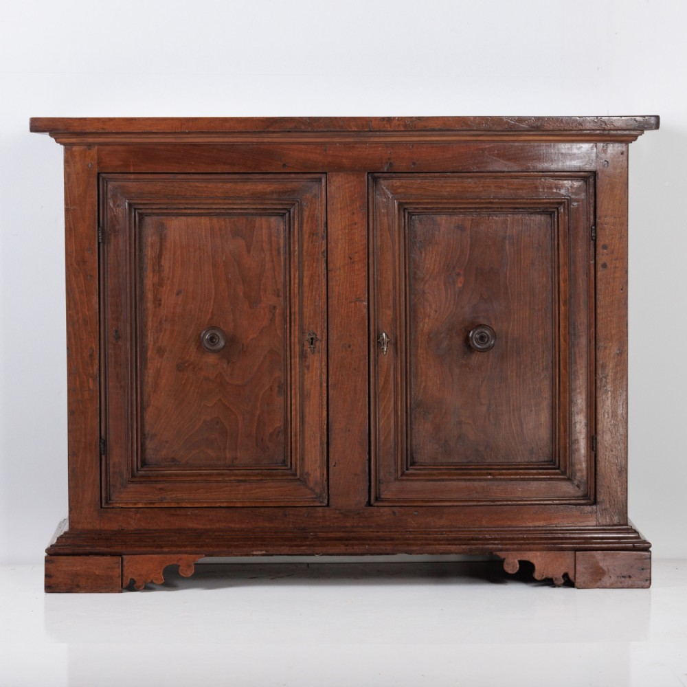 A 19th-century Tuscan walnut cupboard featuring two double-moulded panel doors with turned knobs and a shaped plinth base.