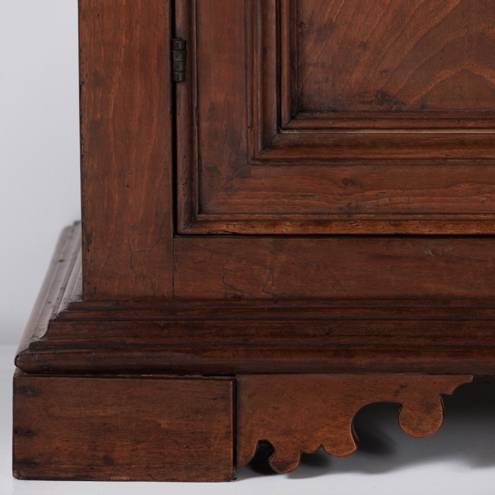 A 19th-century Tuscan walnut cupboard featuring two double-moulded panel doors with turned knobs and a shaped plinth base. View V