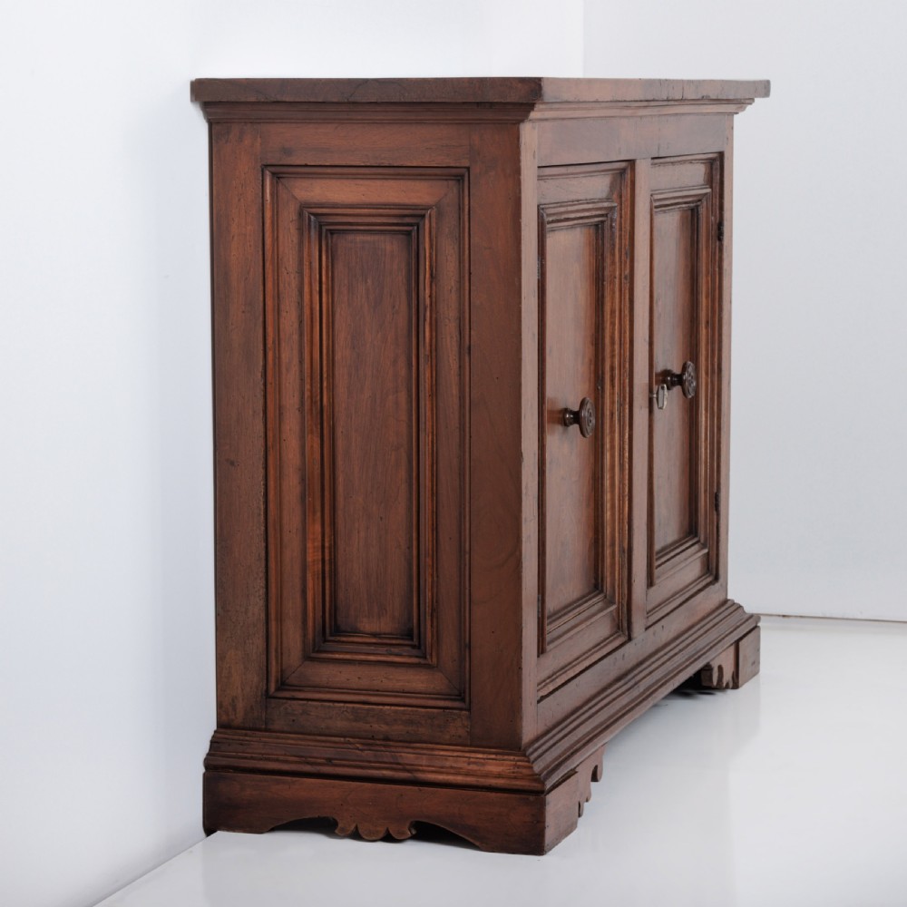 A 19th-century Tuscan walnut cupboard featuring two double-moulded panel doors with turned knobs and a shaped plinth base. View VI