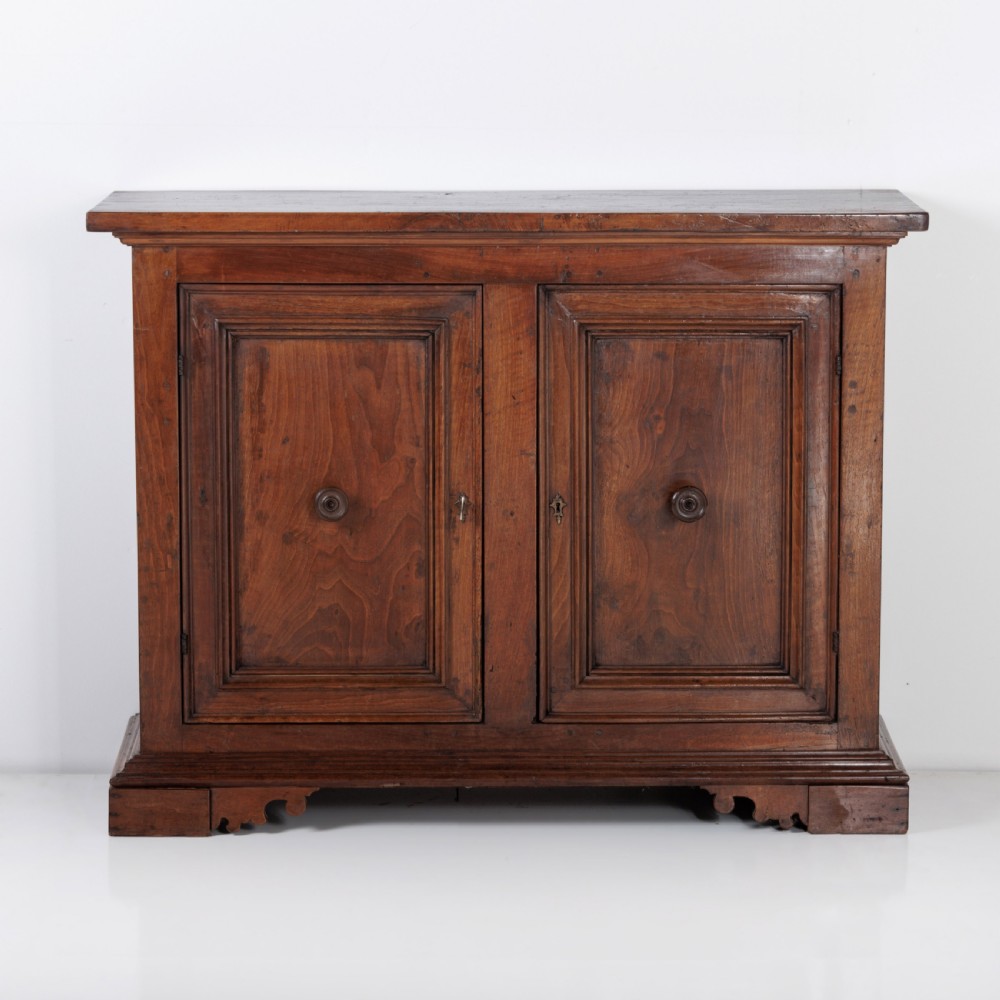 A 19th-century Tuscan walnut cupboard featuring two double-moulded panel doors with turned knobs and a shaped plinth base. View XVI