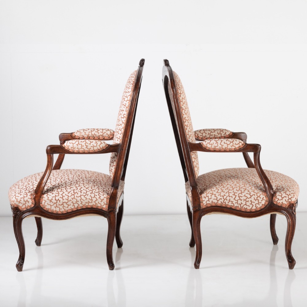 A pair of 19th-century French Louis XV style fauteuil armchairs with carved walnut frames, cabriole legs, brass stud trim, and patterned cream and brown upholstery. View IV