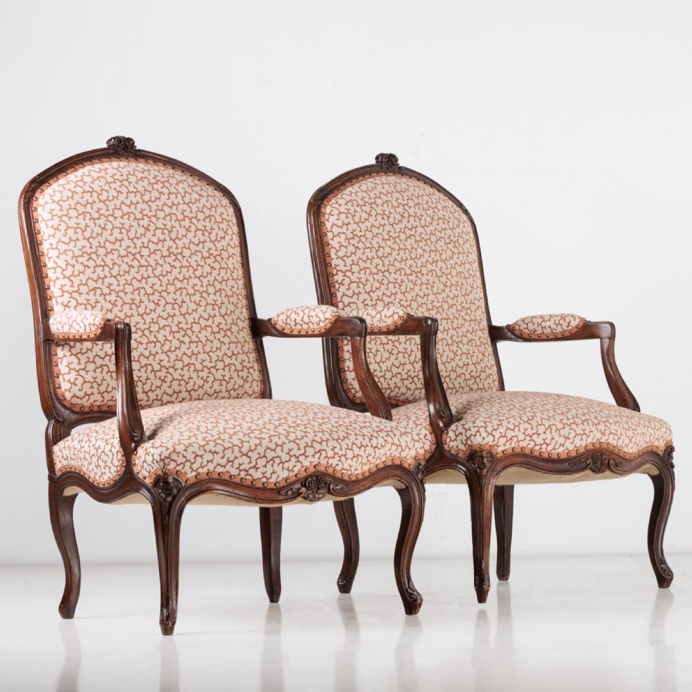 A pair of 19th-century French Louis XV style fauteuil armchairs with carved walnut frames, cabriole legs, brass stud trim, and patterned cream and brown upholstery. View V
