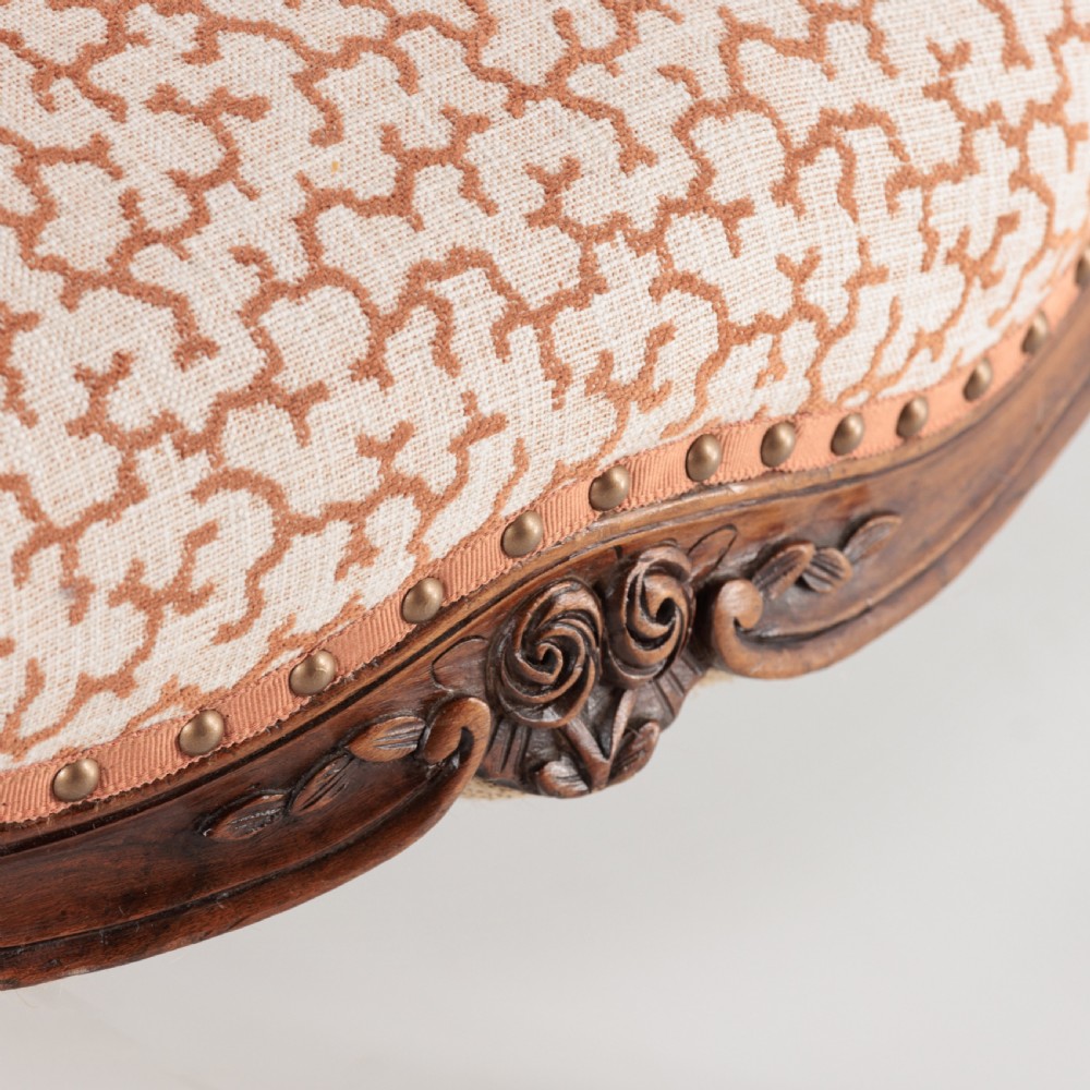A pair of 19th-century French Louis XV style fauteuil armchairs with carved walnut frames, cabriole legs, brass stud trim, and patterned cream and brown upholstery. View X