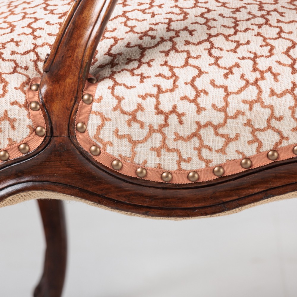 A pair of 19th-century French Louis XV style fauteuil armchairs with carved walnut frames, cabriole legs, brass stud trim, and patterned cream and brown upholstery. View XVI