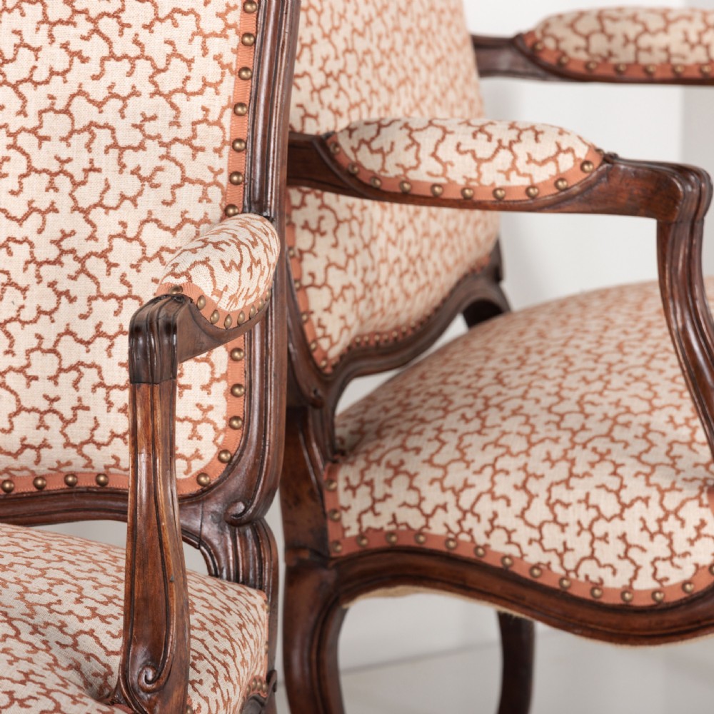 A pair of 19th-century French Louis XV style fauteuil armchairs with carved walnut frames, cabriole legs, brass stud trim, and patterned cream and brown upholstery. View XVII