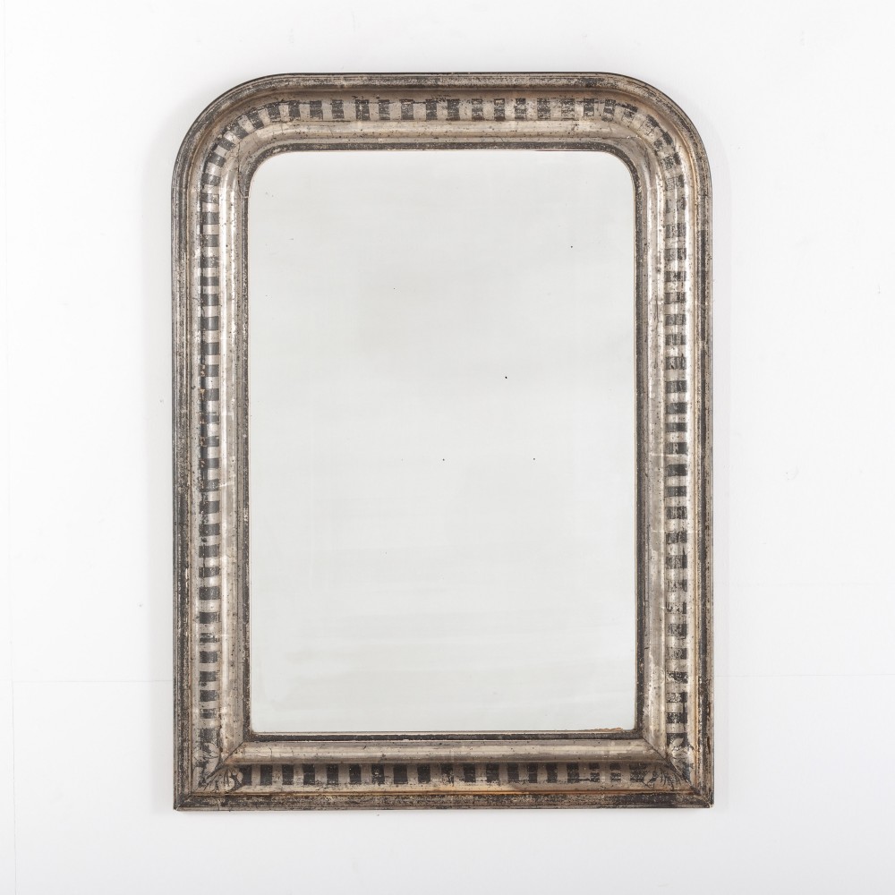 A 19th-century French Louis Philippe wall mirror featuring a silver leaf finish with a striped incised motif, rounded upper corners, and a flat base.