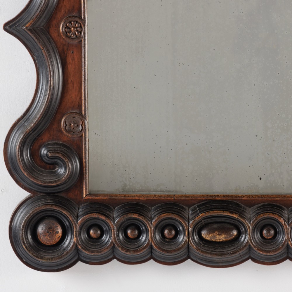 A dark brown carved wood wall mirror featuring elaborate scrollwork, rosette medallions, and a rectangular mirror glass. View III