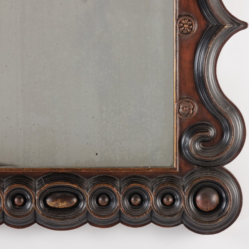 A dark brown carved wood wall mirror featuring elaborate scrollwork, rosette medallions, and a rectangular mirror glass. View IV
