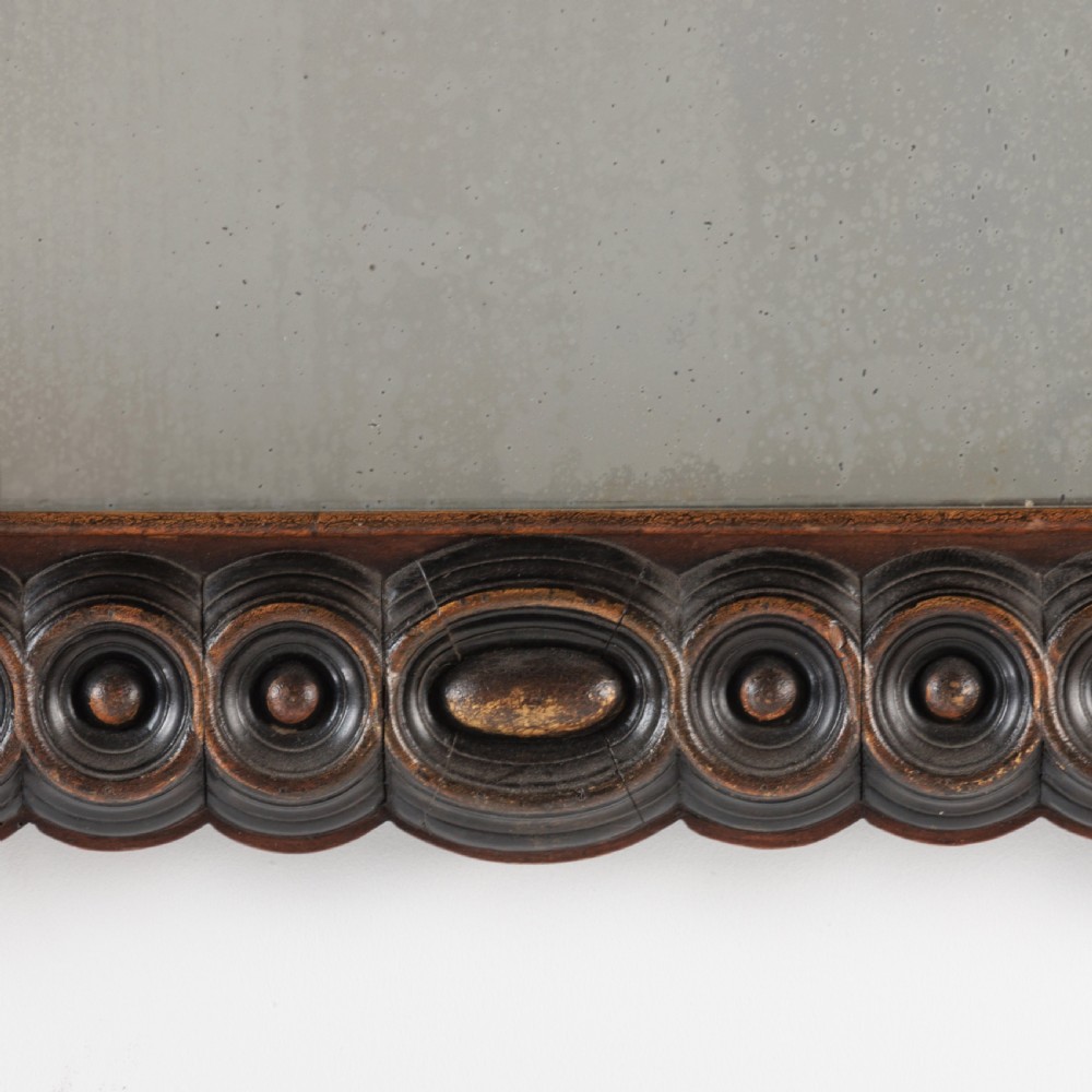 A dark brown carved wood wall mirror featuring elaborate scrollwork, rosette medallions, and a rectangular mirror glass. View V