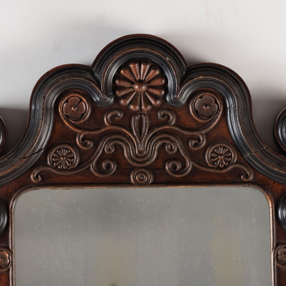 A dark brown carved wood wall mirror featuring elaborate scrollwork, rosette medallions, and a rectangular mirror glass. View VII