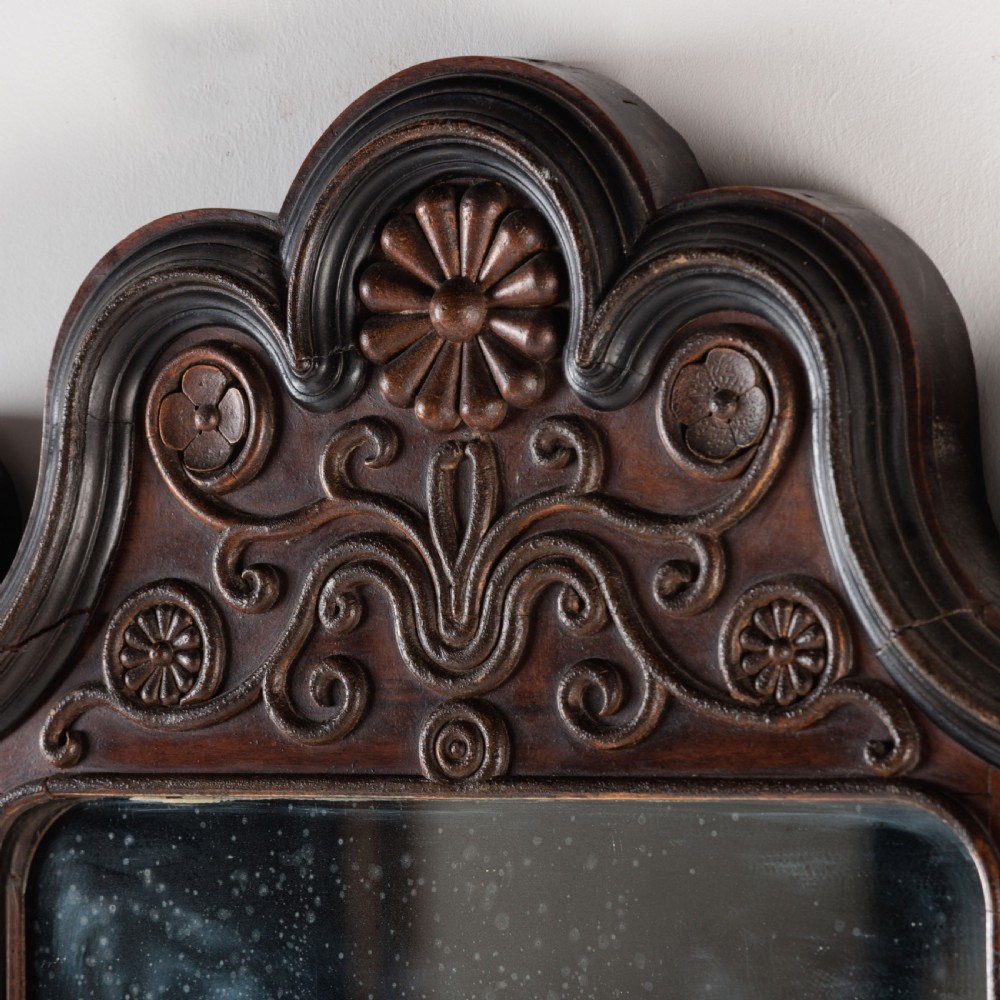 A dark brown carved wood wall mirror featuring elaborate scrollwork, rosette medallions, and a rectangular mirror glass. View VIII