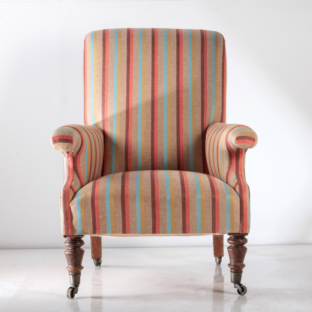 A 19th-century Victorian easy armchair upholstered in vertical stripes of terracotta, blue, beige, and gold with turned timber front legs on brass castors. View II