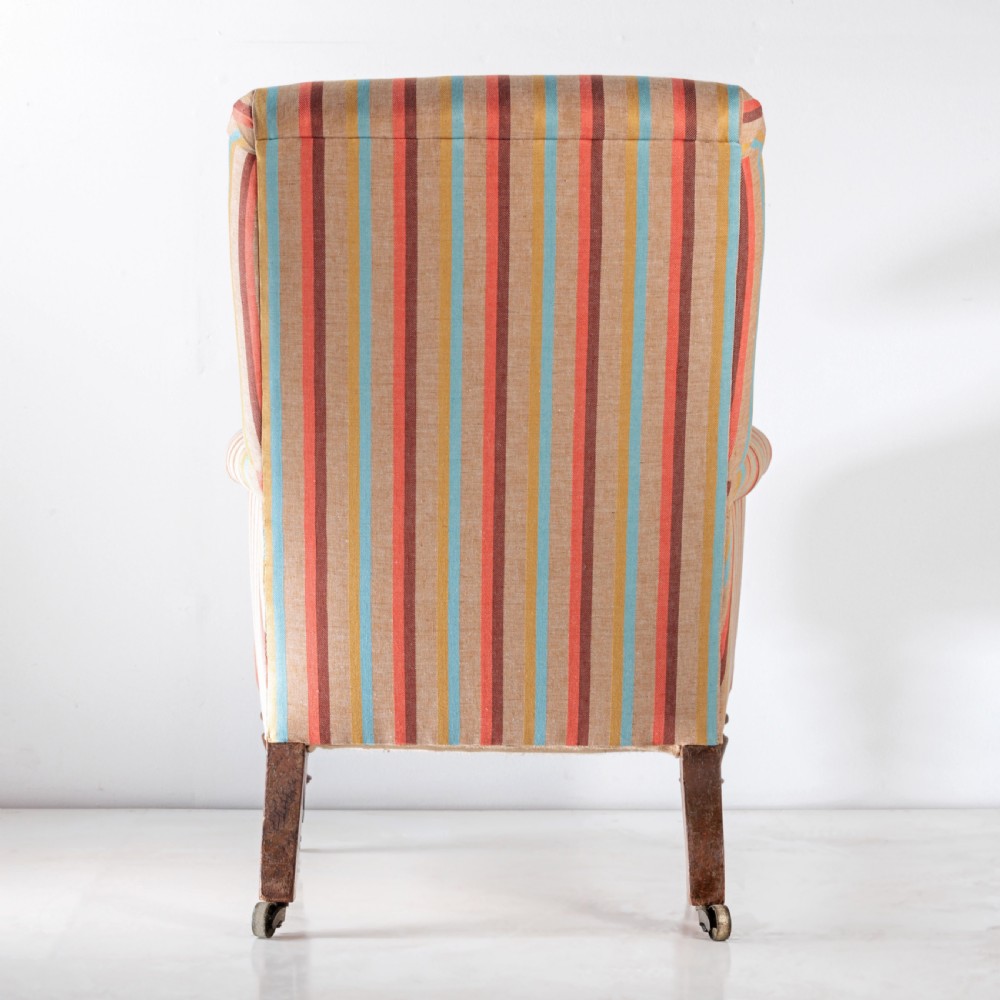 A 19th-century Victorian easy armchair upholstered in vertical stripes of terracotta, blue, beige, and gold with turned timber front legs on brass castors. View III