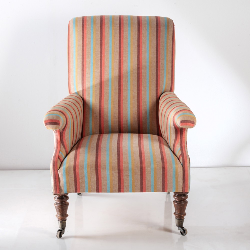 A 19th-century Victorian easy armchair upholstered in vertical stripes of terracotta, blue, beige, and gold with turned timber front legs on brass castors. View VI