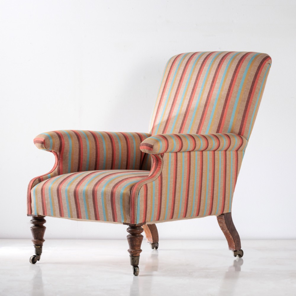 A 19th-century Victorian easy armchair upholstered in vertical stripes of terracotta, blue, beige, and gold with turned timber front legs on brass castors. View VII
