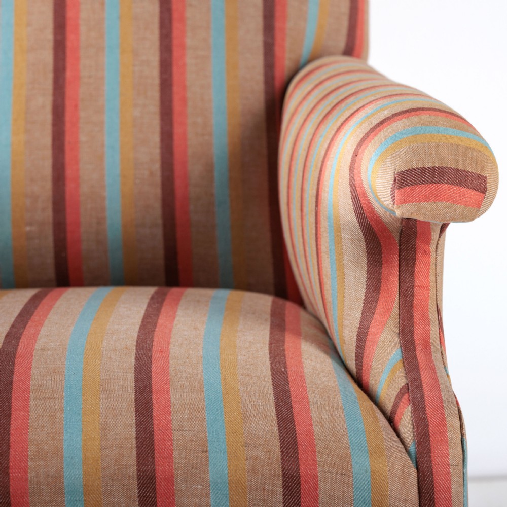 A 19th-century Victorian easy armchair upholstered in vertical stripes of terracotta, blue, beige, and gold with turned timber front legs on brass castors. View VIII