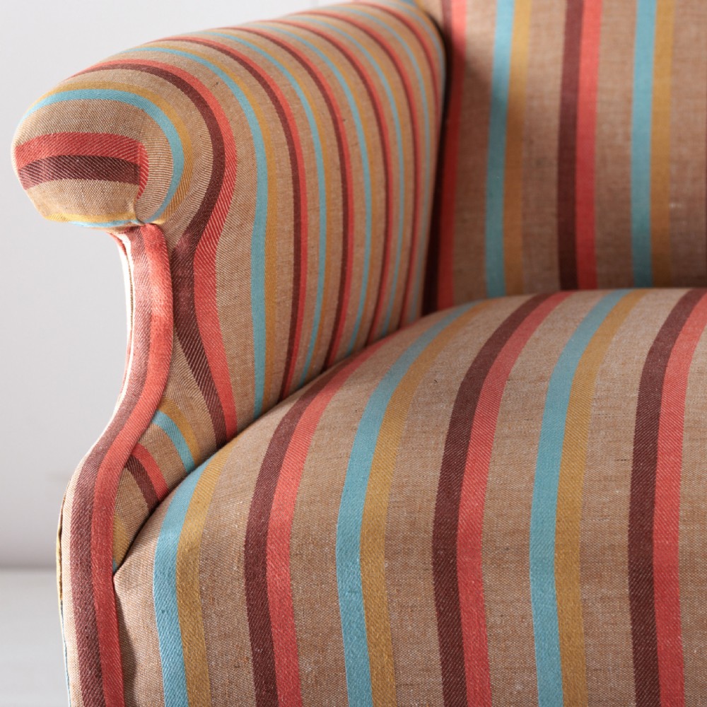A 19th-century Victorian easy armchair upholstered in vertical stripes of terracotta, blue, beige, and gold with turned timber front legs on brass castors. View IX