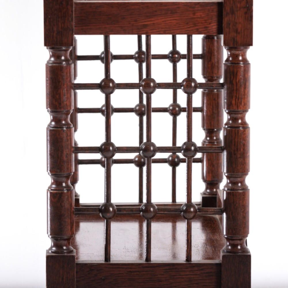 A dark oak Aesthetic Movement side table featuring turned spindle supports, side spindle galleries, three tiers, and legs terminating in castors. View VIII
