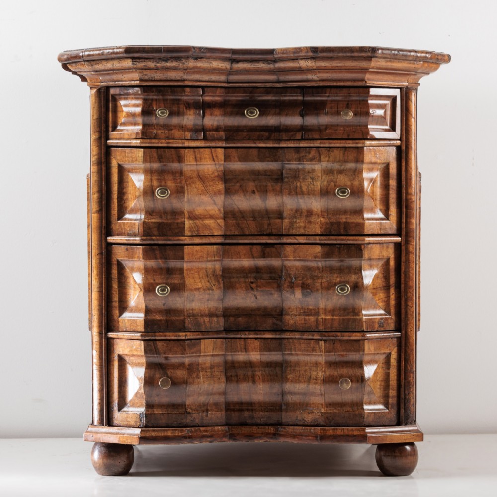 An 18th-century Bavarian walnut chest of drawers featuring a serpentine front, four moulded drawers with brass knobs, panelled sides, and turned bun feet. View III