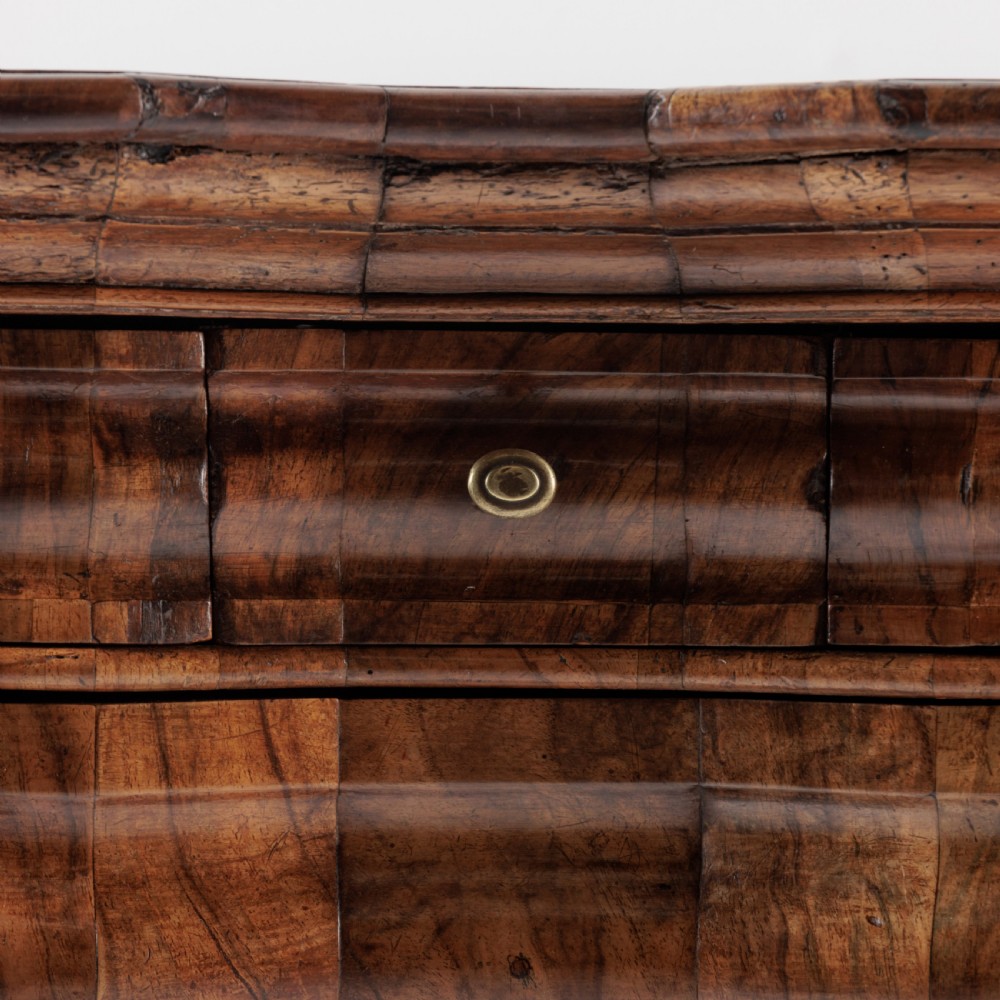An 18th-century Bavarian walnut chest of drawers featuring a serpentine front, four moulded drawers with brass knobs, panelled sides, and turned bun feet. View VIII