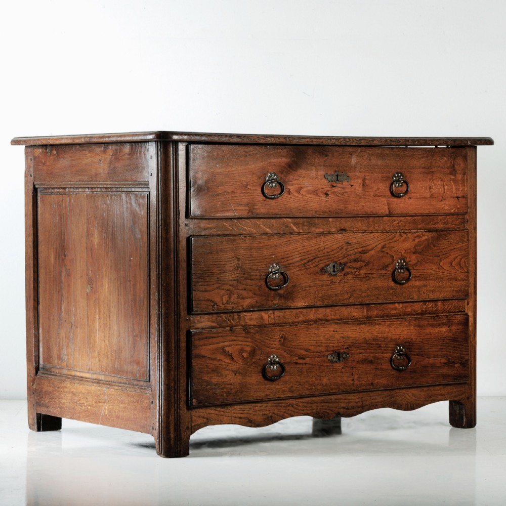 A nineteenth-century provincial oak chest of drawers with three full-width drawers featuring metal drop handles and decorative keyhole escutcheons. View III