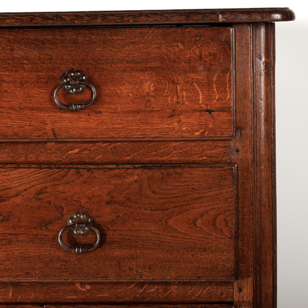 A nineteenth-century provincial oak chest of drawers with three full-width drawers featuring metal drop handles and decorative keyhole escutcheons. View VI