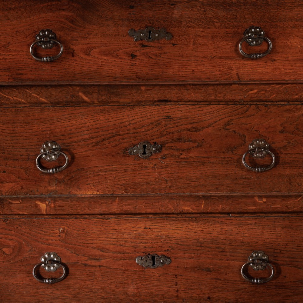 A nineteenth-century provincial oak chest of drawers with three full-width drawers featuring metal drop handles and decorative keyhole escutcheons. View VII