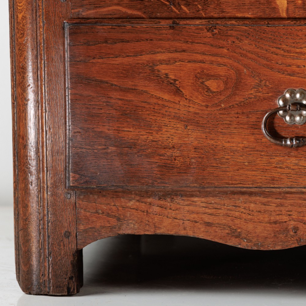A nineteenth-century provincial oak chest of drawers with three full-width drawers featuring metal drop handles and decorative keyhole escutcheons. View VIII