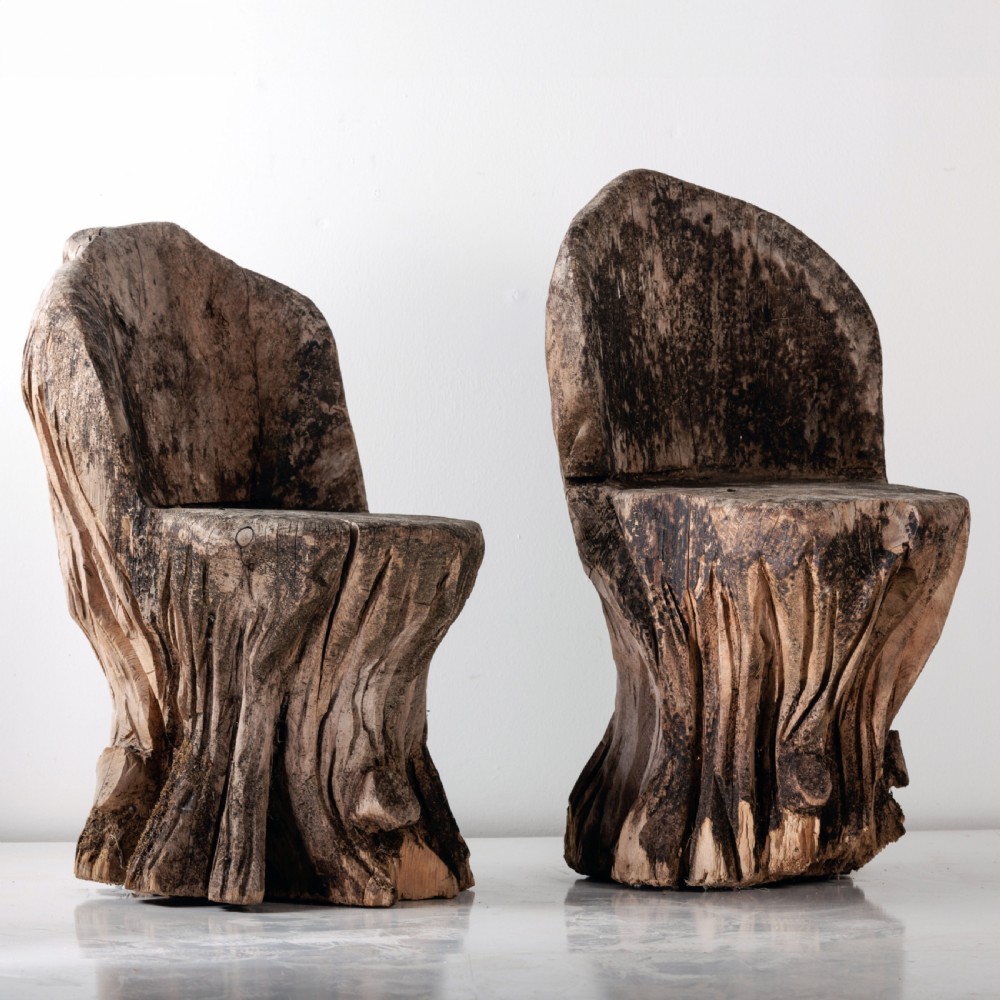 A pair of hand-carved dugout garden seats crafted from solid tree trunks with weathered timber surfaces.