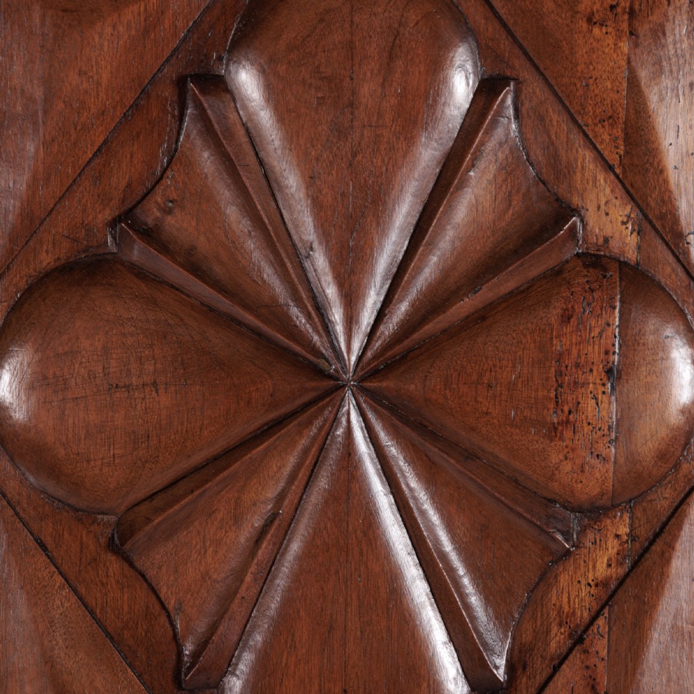 A large seventeenth-century Italian walnut cabinet featuring two tall panelled doors with carved geometric star relief motifs, framed by moulded side pilasters and resting on bracket feet. View VIII