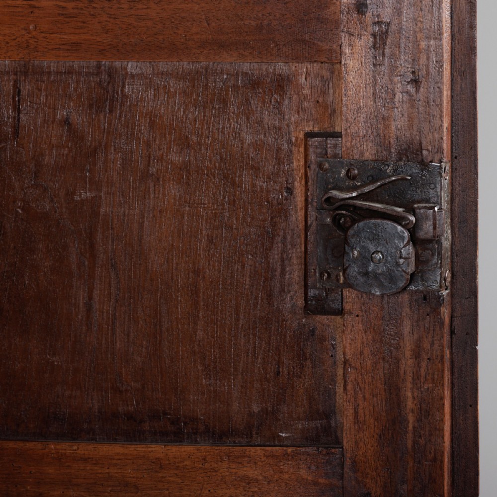 A large seventeenth-century Italian walnut cabinet featuring two tall panelled doors with carved geometric star relief motifs, framed by moulded side pilasters and resting on bracket feet. View IX