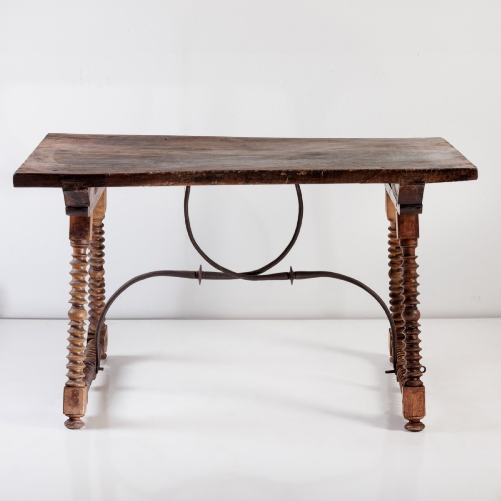 An 18th-century Spanish walnut trestle table featuring a solid timber top, spool-turned legs, and a curved wrought iron stretcher. View III