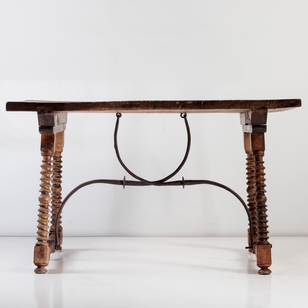 An 18th-century Spanish walnut trestle table featuring a solid timber top, spool-turned legs, and a curved wrought iron stretcher. View IV