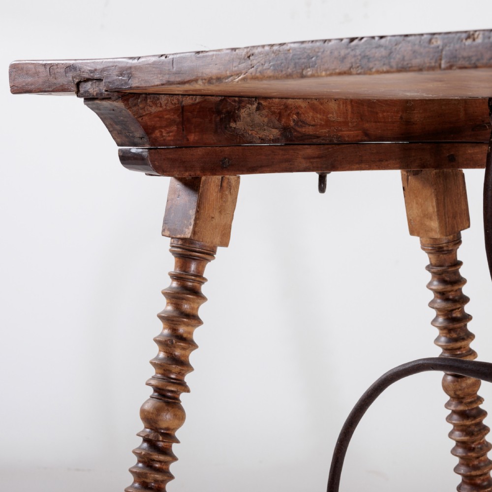An 18th-century Spanish walnut trestle table featuring a solid timber top, spool-turned legs, and a curved wrought iron stretcher. View V