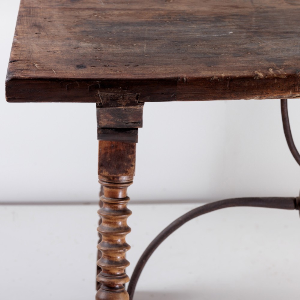 An 18th-century Spanish walnut trestle table featuring a solid timber top, spool-turned legs, and a curved wrought iron stretcher. View VII