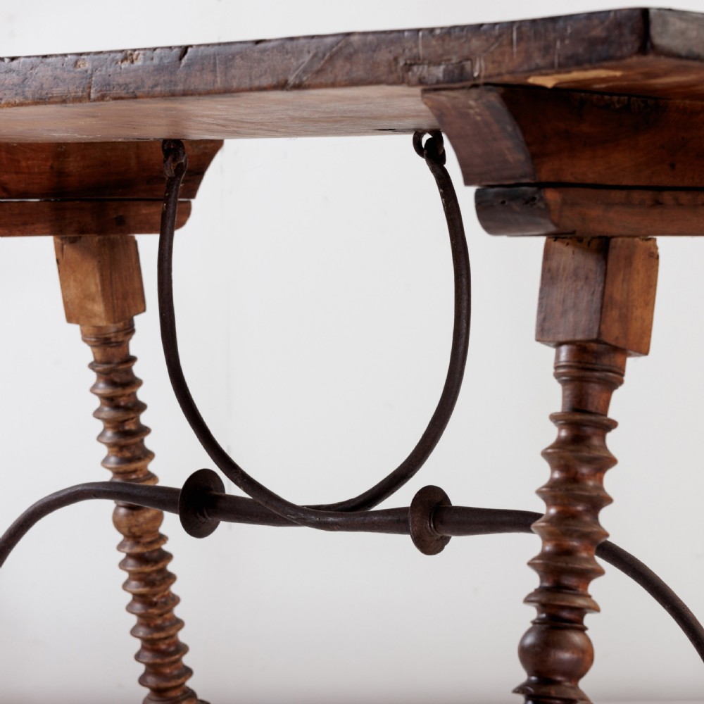 An 18th-century Spanish walnut trestle table featuring a solid timber top, spool-turned legs, and a curved wrought iron stretcher. View VIII