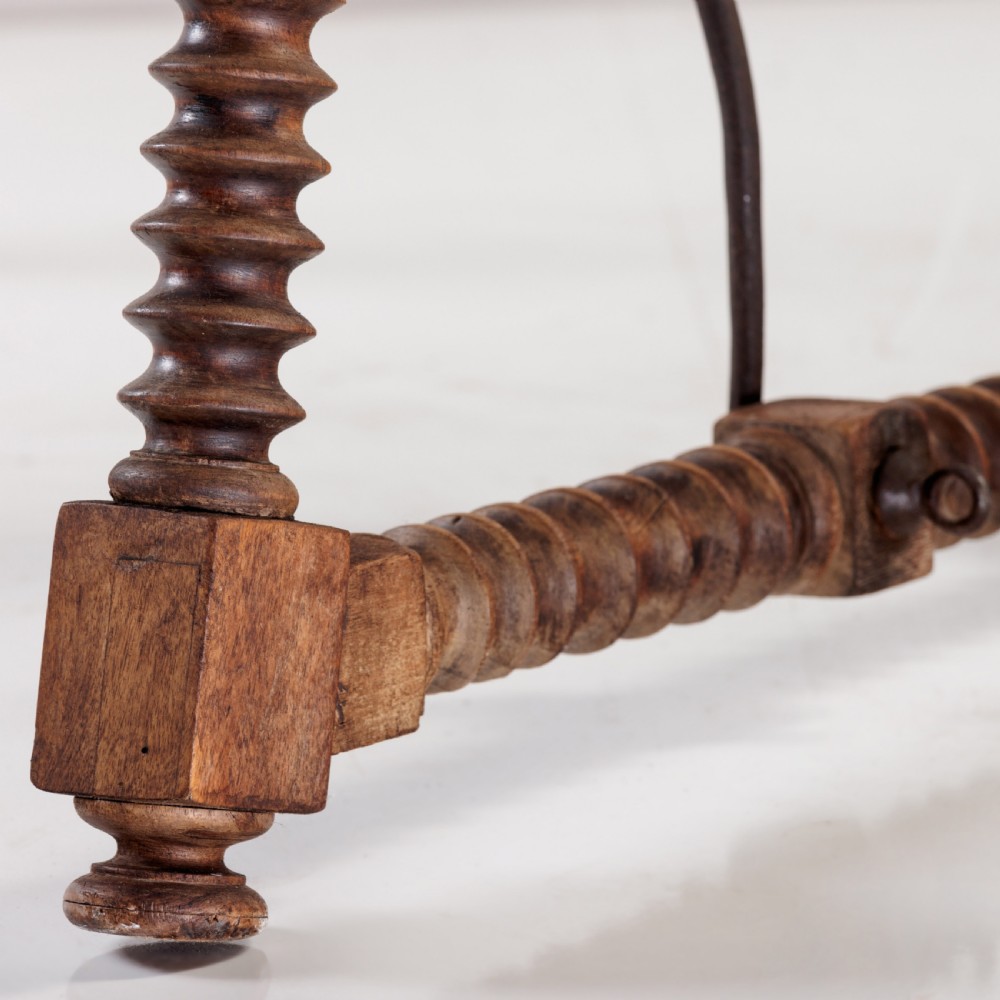 An 18th-century Spanish walnut trestle table featuring a solid timber top, spool-turned legs, and a curved wrought iron stretcher. View IX
