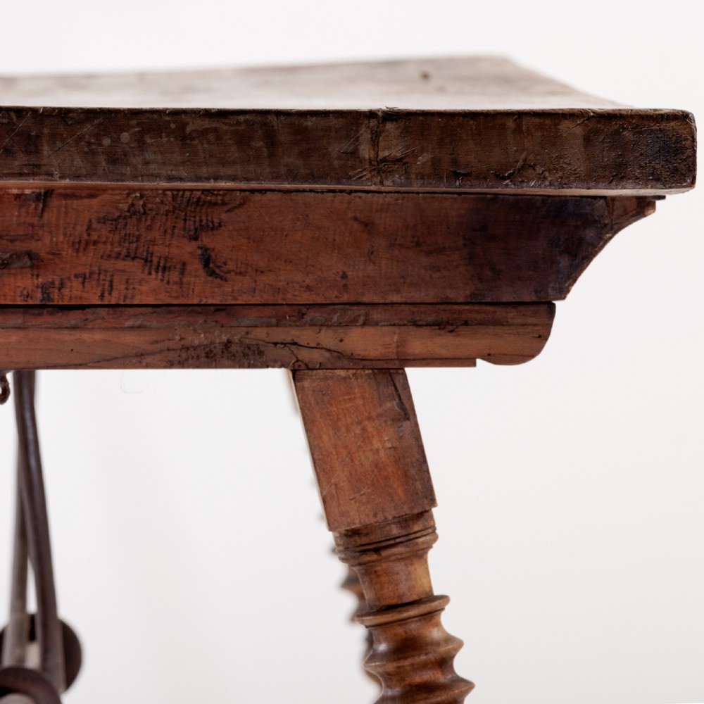 An 18th-century Spanish walnut trestle table featuring a solid timber top, spool-turned legs, and a curved wrought iron stretcher. View XI